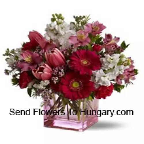 Roses rouges, tulipes rouges et fleurs assorties avec des garnitures saisonnières arrangées magnifiquement dans un vase en verre