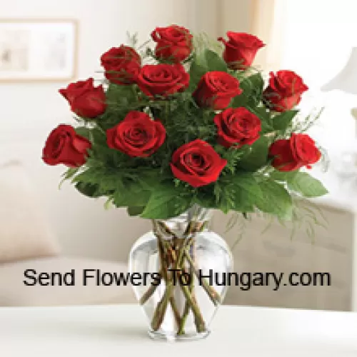 11 Roses rouges avec quelques fougères dans un vase en verre