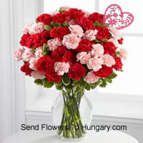37 Garofani (19 rossi e 18 rosa) con riempitivi stagionali e bastoncino a forma di cuore in un vaso di vetro